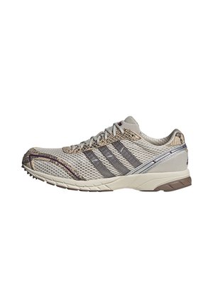 Lichtgrijze mesh hardloopschoen met donkergrijze strepen, slangenhuidpatroon details en beige zool, zijaanzicht op een witte achtergrond.