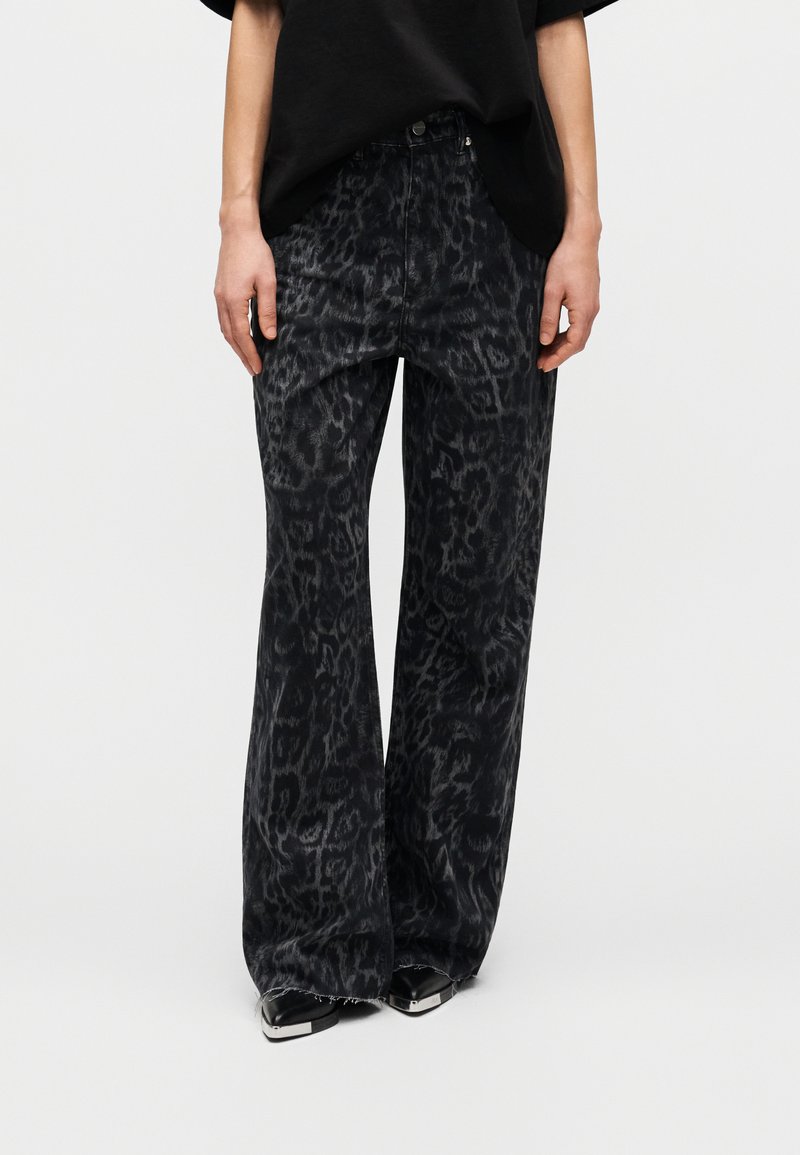Μαύρο τζιν με φαρδιά παντελόνια και διακριτικό σχέδιο λεοπάρ, κατασκευασμένο από απαλό τζιν ύφασμα. Διαθέτει κλασικό σχέδιο με πέντε τσέπες και ελαφρώς ξεφτισμένο τελείωμα.
