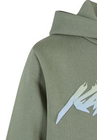 Primer plano de sudadera verde con capucha doblada y gráfico de llama estilizada en azul claro en el pecho.