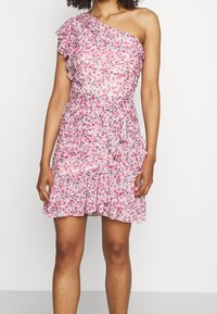 Robe fleurie rose avec une épaule, détail volants et jupe à niveaux. Fabriquée en tissu léger, avec un lien à la taille.