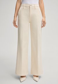Pantaloni beige a gamba larga in cotone, con vita alta, tasche frontali e chiusura con bottone. Tessuto liscio con bordi puliti.