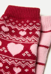 Skarpetki dziane w kolorze czerwonym i różowym z wzorem serc, z prążkowanym wykończeniem i miękką fakturą. Projekt zawiera naprzemienne kolory i motywy.