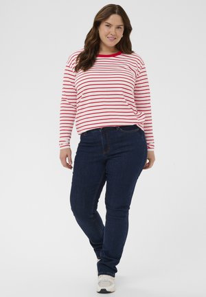 Rdeče-bela črtasta majica z dolgimi rokavi in okrolim izrezom, kombinirana s temno modrimi otesanimi kavbojkami in svetlo obarvanimi supergami.