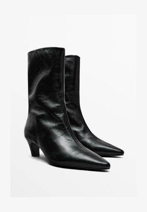 Black leather ankle boots with a pointed toe, slim block heel, and smooth finish; feature a zip closure at the back.