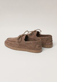 Brown suede shoes with a low-cut design, lace-up closure, and a woven jute sole. Reinforced eyelets are visible along the sides.