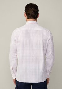 Camicia a maniche lunghe a quadri bianca con motivo a griglia rossa, caratterizzata da colletto button-down e aperture laterali. Tessuto morbido.