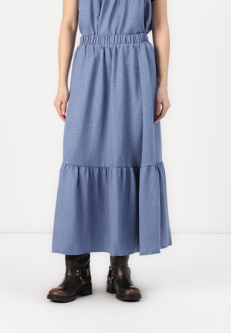 Blå chambray maxi-skjørt med elastisk midjebånd, med lagdelt hem og glatt tekstur, kombinert med brune skinn ankelstøvler.