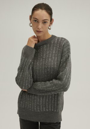 Gray knitted sweater with ribbed texture, featuring silver horizontal stripes and a crew neckline. Loose fit with long sleeves.