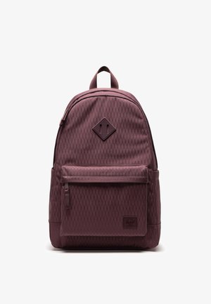 Bordeauxfarbener Rucksack mit Rautenmuster, Frontreißverschlusstasche, Tragegriff oben und Aufnäher, vor weißem Hintergrund fotografiert.