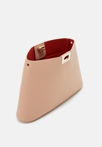 Borsa a mano in pelle beige con forma geometrica, hardware in oro e interno rosso. Presenta una chiusura a morsetto superiore e un'etichetta del marchio all'interno.
