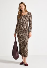 Klänning med leopardtryck, långärmad och fyrkantig halsringning; slät tyg, figurnära silhuett, kombinerad med en bordeauxfärgad handväska.