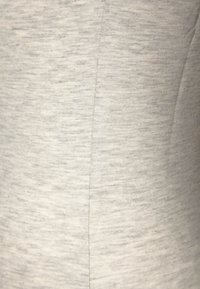 Lähes valkoinen venyvä kangas lähikuvassa, jossa on hienovarainen heather-tekstuuri, vaaleita viivoja ja saumoja. Sujuva ja pehmeä ulkonäkö.