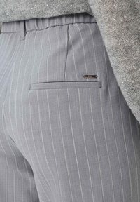 Grijze pinstripe broek van lichtgewicht stof, met een strak ontwerp, elastische tailleband, zij- en achterzakken, en een metalen merklabel.