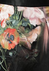 Tissu à motif floral présentant des fleurs rouges et roses vibrantes avec un feuillage vert sur un fond noir. Texture lisse et design fluide.