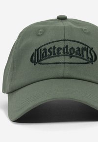 Zöld pamut sapka sötétzöld "Wastedparts" logóval, amely hímzéssel készült. Ívelt karimával és texturált anyaggal rendelkezik. Hatpaneles kialakítás, szellőző lyukakkal.