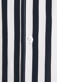Camicia a righe con strisce verticali blu navy e bianche, in tessuto di cotone, con dettagli di bottoni e cuciture visibili lungo la pattina dei bottoni.