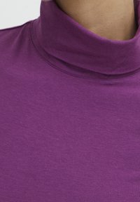 Lila polotröja med en mjuk, slät yta. Tätsittande design med hög hals och subtila sömdetaljer.