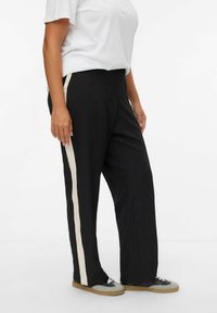 Pantalons larges noirs avec des rayures cream sur les côtés; fabriqués à partir d'un tissu doux, offrant une coupe décontractée, une taille élastique et un design minimal.