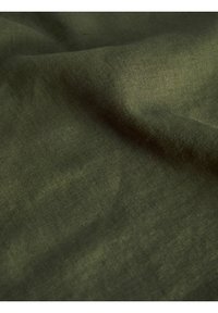 Tejido verde oscuro con una superficie suave y ligeramente texturizada, que muestra sutiles variaciones en color y patrón de tejido. Sin hardware ni acentos notables.
