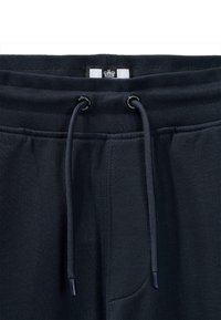 Námornícke bavlnené tepláky s nastaviteľným pásom, ktoré majú predné vrecko a textúrovanú tkaninu pre komfort. Akcenty obsahujú brandované kovové prvky.