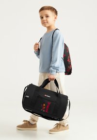 Borsa duffel nera con stampa grafica, manici superiori e tracolla staccabile. Presenta una tasca con zip e un tessuto robusto e testurizzato.
