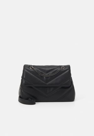 Schwarze Ledertasche mit gesteppter Chevron-Struktur und silbernem Kettenriemen vor weißem Hintergrund.