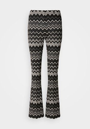 Pantaloni svasati a zigzag bianco e nero con una texture di tessuto liscia, dotati di una vita e senza dettagli hardware visibili.
