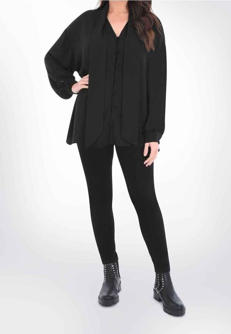 Blusa nera oversize con maniche lunghe, abbinata a leggings neri aderenti e stivaletti con dettagli borchiati.