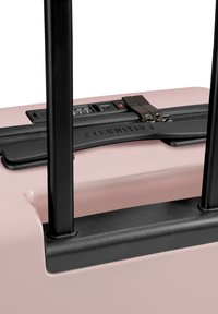 Hartschalentrolley in sanftem Rosa mit schwarzem Griff und Reißverschlüssen. Verfügt über ein Zahlenkombinationsschloss, strukturierte Oberfläche und einen markierten schwarzen Gurt.