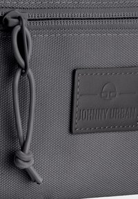 Borsa in tessuto grigio con una finitura texturizzata, dotata di una cerniera e di un'etichetta in gomma nera con la scritta "JOHNNY URBAN" in rilievo.