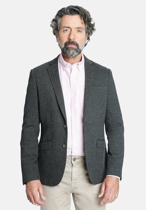Blazer gris texturizado con dos botones y solapas acanaladas, sobre una camisa de cuello rosa claro, combinado con pantalones de color claro.