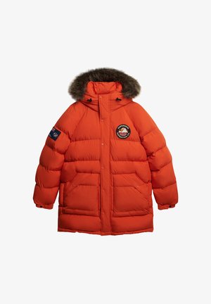 Giacca puffer arancione brillante con cappuccio foderato in pelliccia sintetica, dotata di un patch con logo, chiusure a scatto e tasche frontali.