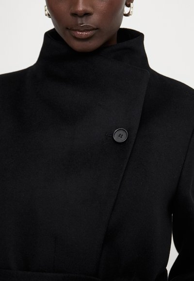 Black wool coat featuring a high collar, side button closure, and a smooth texture. Simple design with no patterns or additional adornments.