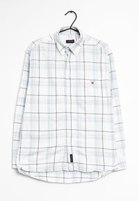 Camisa de cuadros de manga larga y ligera en blanco y azul claro, con collar abotonado, bolsillo en el pecho y dobladillo curvado. Logo de la marca visible.