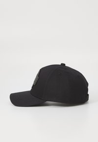 Casquette de baseball noire en coton avec une visière incurvée, présentant un patch texturé noir à l'avant et une sangle réglable à l'arrière.
