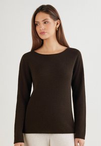 Brauner Pullover mit langen Ärmeln und rundem Ausschnitt, gefertigt aus strukturiertem Stoff. Verfügt über eine taillierte Silhouette sowie gerippte Bündchen und Saum.