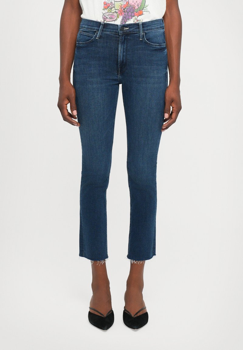 Donkerblauwe denim jeans met een slanke pasvorm, uitgerafelde zoom en een vijf-pocket ontwerp. Gecombineerd met zwarte puntige hakken.