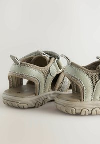 Ljusgrå utomhussandaler med nätdetaljer, vadderad innersula och gummisula. Har justerbara remmar och öppen design för god ventilation.