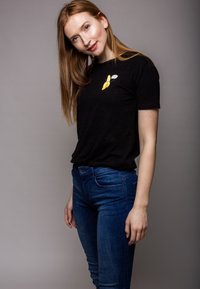 Black short-sleeve t-shirt with a yellow banana graphic; paired with blue fitted jeans. Smooth texture, casual fit.