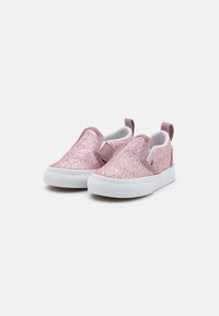 Rozā mirdzošas slip-on kurpes ar baltu gumijas zoli, ar mīkstu iekšējo oderi un vilkšanas cilpu aizmugurē, lai tās būtu viegli uzvelkamas.