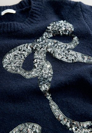 Pulover din lână de culoare bleumarin, cu un design mare din paiete argintii care seamănă cu o panglică sau un vârtej. Textură tricotată, cu guler cu nervuri.