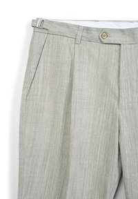Pantaloni in lino beige chiaro con tasche laterali, chiusura a bottone e fibbia laterale regolabile in vita.