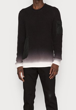 Jersey texturizado negro con un efecto ombré que se desvanece a blanco en el dobladillo. Presenta parches de tela negra en los laterales y en las mangas.