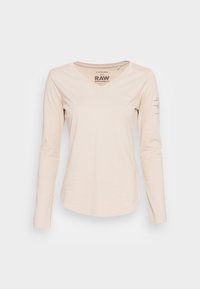 Ljusbeige långärmad V-ringad t-shirt i mjukt tyg. Har tryckt logotyp på bröstet och höger ärm. Slät textur, avslappnad design.