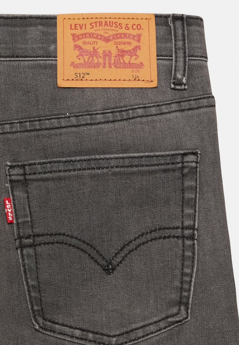 Schwarze Denim-Jeans mit gestickter Gesäßtasche und rotem Levi's-Tab. Verfügt über ein braunes Lederetikett mit Markendetails. Klassischer Schnitt, strapazierfähiges Material.