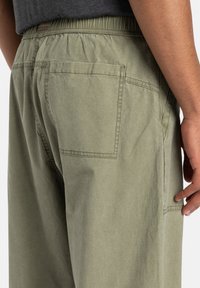 Elastic-waist, olive-green shorts made of lightweight fabric. Features two back pockets and a clean, tailored design without embellishments.