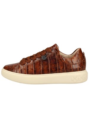 Lage bruine leren sneaker met krokodillenpatroon, dikke crèmekleurige zool, brede bruine veters en een kleine ronde metalen hanger aan de zijkant.