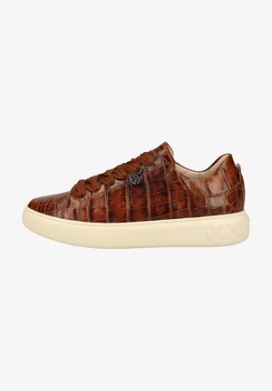 Baskets basses en cuir marron avec motif crocodile, semelle épaisse couleur crème, larges lacets marron et petit pendentif métallique rond sur le côté.