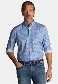 lichtblauw overhemd met knopen en een gepattern ontwerp, met opgerolde lange mouwen, gecombineerd met blauwe jeans en een geweven marineblauwe riem.