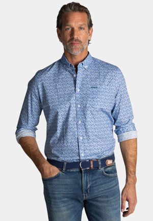 lichtblauw overhemd met knopen en een gepattern ontwerp, met opgerolde lange mouwen, gecombineerd met blauwe jeans en een geweven marineblauwe riem.